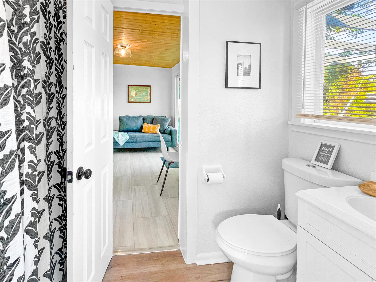 A bathroom with a toilet and vanity opens into a living area with a blue sofa — 1114 N M Street, FL 33460, FL