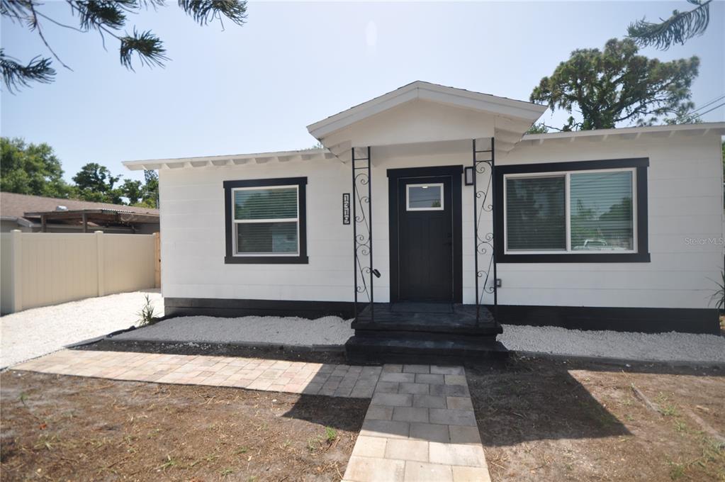 A single-story white house with black trim, a front porch, and a paver walkway — 1319 S 56TH STREET, GULFPORT, FL