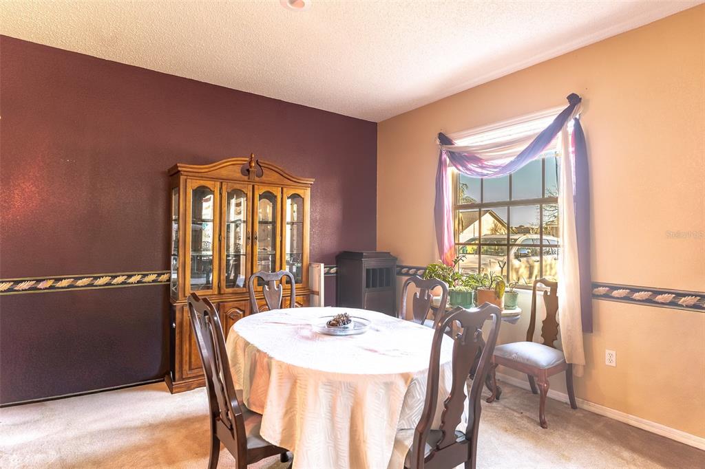A dining room features a wooden hutch, a round table with chairs, and a window — 4317 DINNER LAKE DRIVE, LAKE WALES, FL