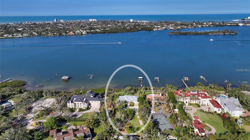 An aerial view shows a waterfront house surrounded by trees and a tennis court — 1440 KIMLIRA LANE, SARASOTA, FL