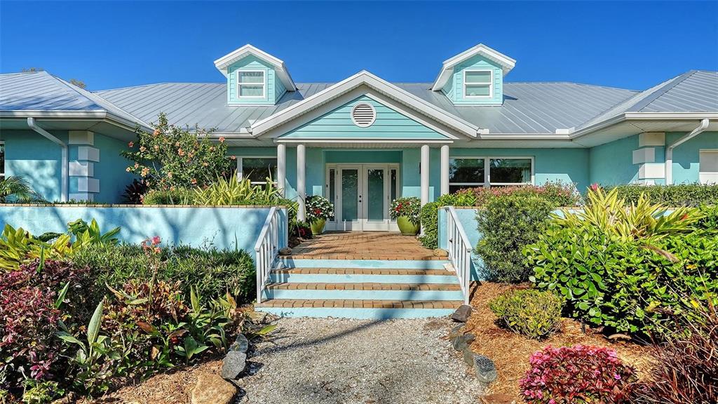 A light blue house with a metal roof and a front porch with steps — 1440 KIMLIRA LANE, SARASOTA, FL