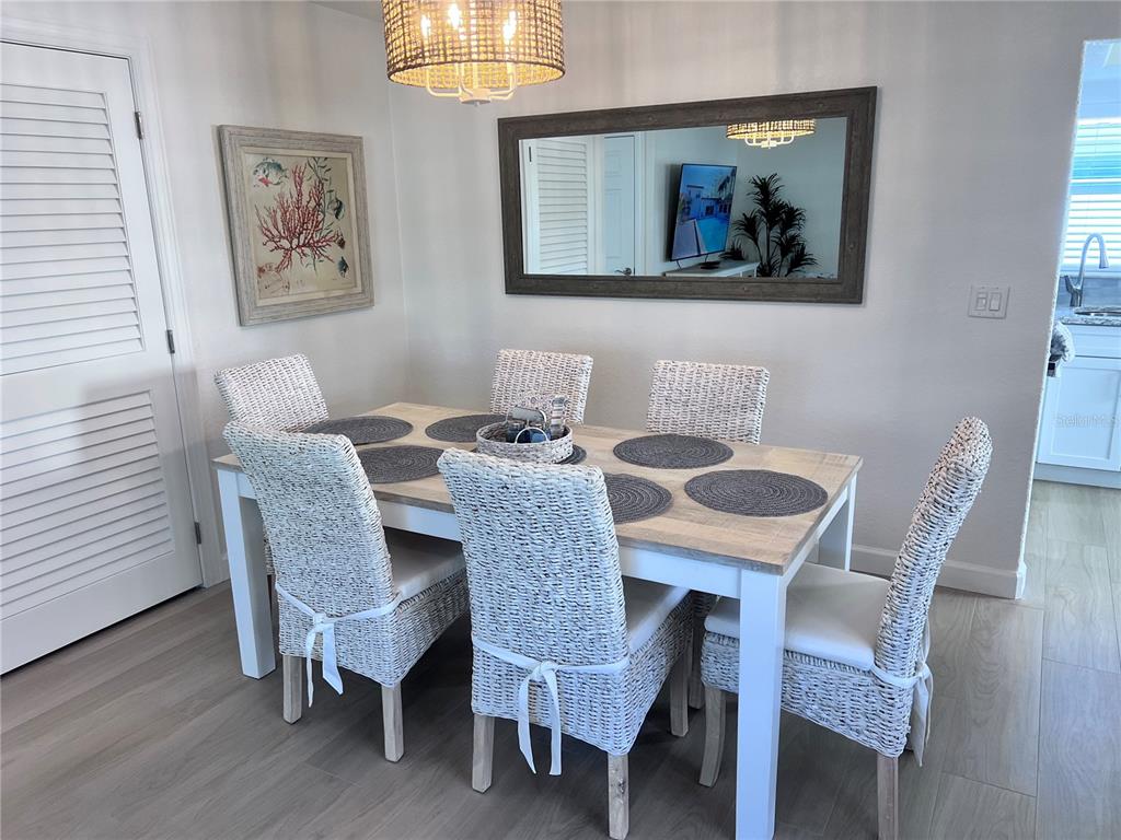 A dining room features a wooden table with six wicker chairs and a wall mirror — 6154 MIDNIGHT PASS ROAD UNIT A11, SARASOTA, FL