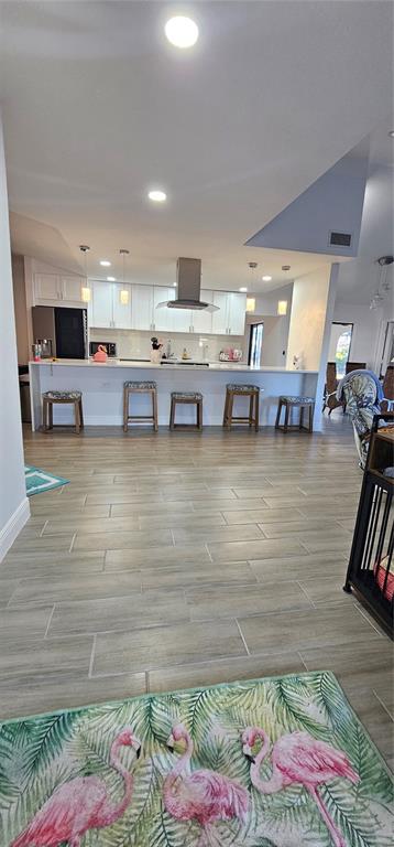 A kitchen with white cabinets, a breakfast bar with stools, and light wood-look tile flooring — 2408 MONTPELIER ROAD, PUNTA GORDA, FL