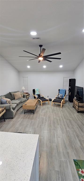 A living room features gray tile flooring, a large ceiling fan, and neutral-toned furniture — 2408 MONTPELIER ROAD, PUNTA GORDA, FL