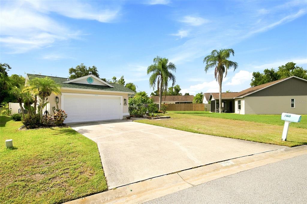A single-story house with a white garage door, a concrete driveway, and two palm trees — 7809 34TH COURT E, SARASOTA, FL
