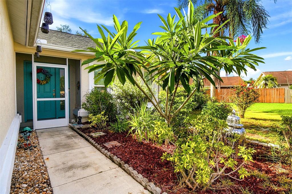 A concrete walkway leads to a teal front door with a white screen door — 7809 34TH COURT E, SARASOTA, FL