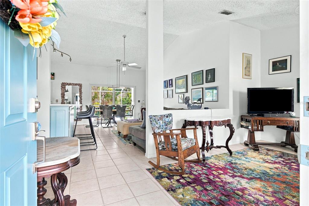 A kitchen features mint green cabinets, white countertops, a tiled backsplash, and a sliding glass door — 7809 34TH COURT E, SARASOTA, FL