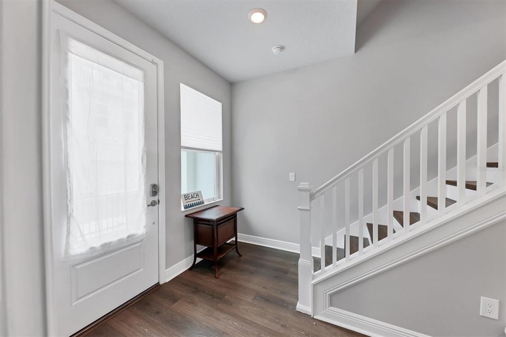 An entryway features dark wood flooring, a white staircase, and a small wooden side table — 2329 LINDSTROM STREET, SARASOTA, FL