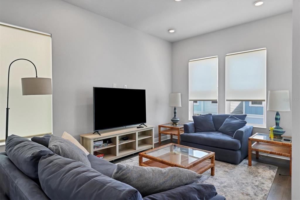 A living room features a blue sofa, a television on a console, and two windows — 2329 LINDSTROM STREET, SARASOTA, FL