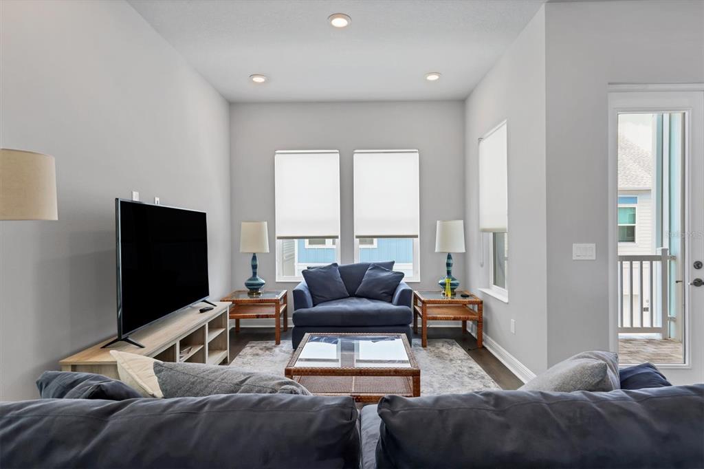 A living room features a blue sofa, a television on a stand, and a balcony door — 2329 LINDSTROM STREET, SARASOTA, FL