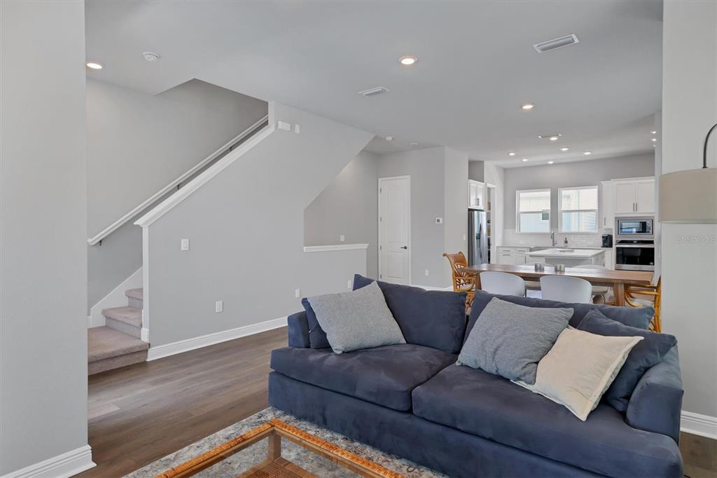 A living room with a blue sofa faces a staircase and an open-concept kitchen — 2329 LINDSTROM STREET, SARASOTA, FL