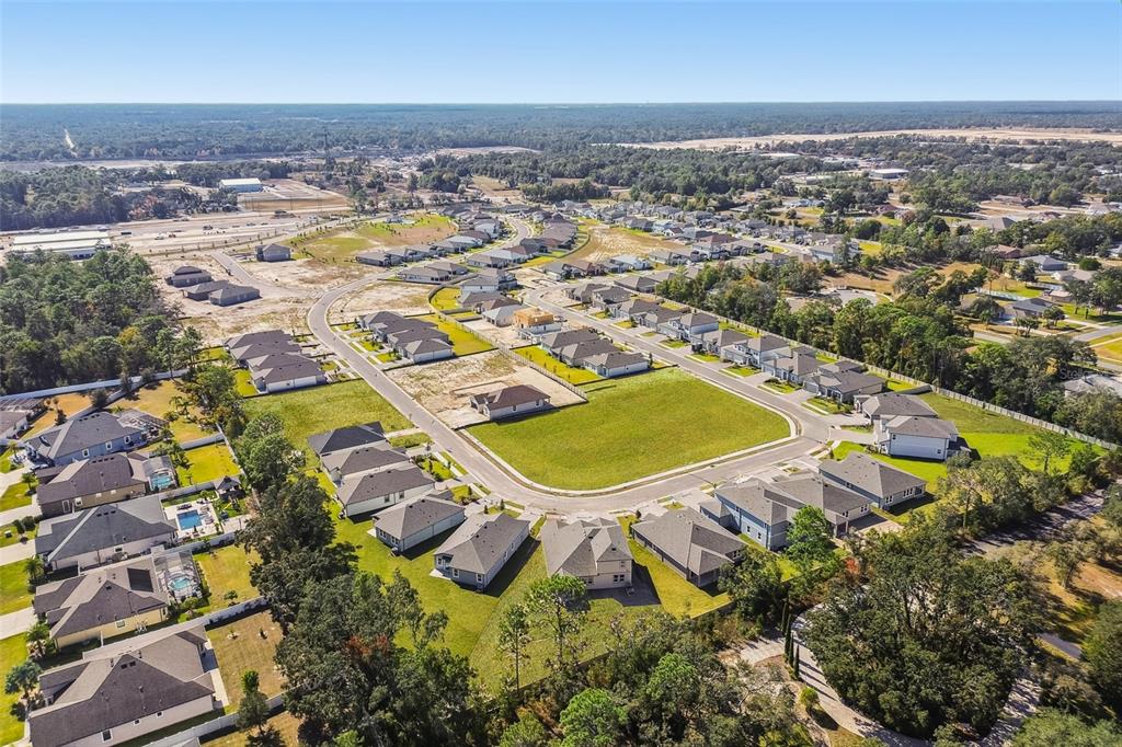An aerial view shows a suburban neighborhood with single-family homes surrounding a central grassy lot — 105 NORTHBANK LANE, SPRING HILL, FL