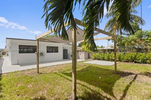 A backyard features a wooden pergola with a shade sail over a grassy lawn — 3125 NW 21st Ct # 01, Miami FL 33142, MIAMI, FL