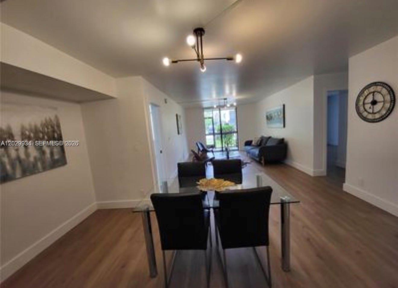 A dining area with a glass table and black chairs leads into a living room — 733 SE 1st Way # 109, Deerfield Beach FL 33441, DEERFIELD BEACH, FL