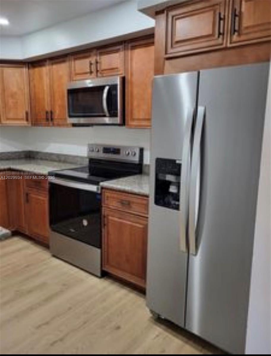 A kitchen features wood cabinets, stainless steel appliances, and light-colored flooring — 733 SE 1st Way # 109, Deerfield Beach FL 33441, DEERFIELD BEACH, FL