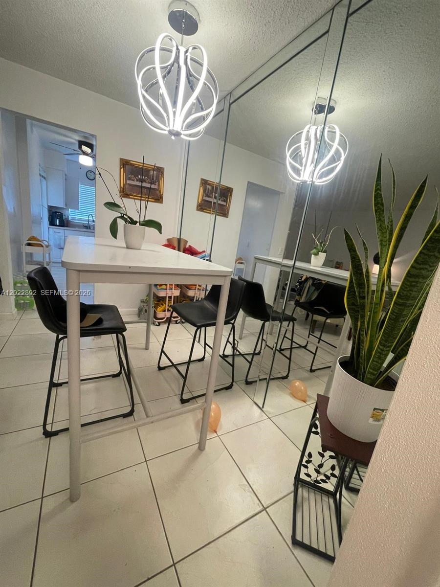 A dining area features a white table, black stools, a modern light fixture, and mirrored walls — 201 NE 14th Ave # 5A, Hallandale Beach FL 33009, HALLANDALE BEACH, FL