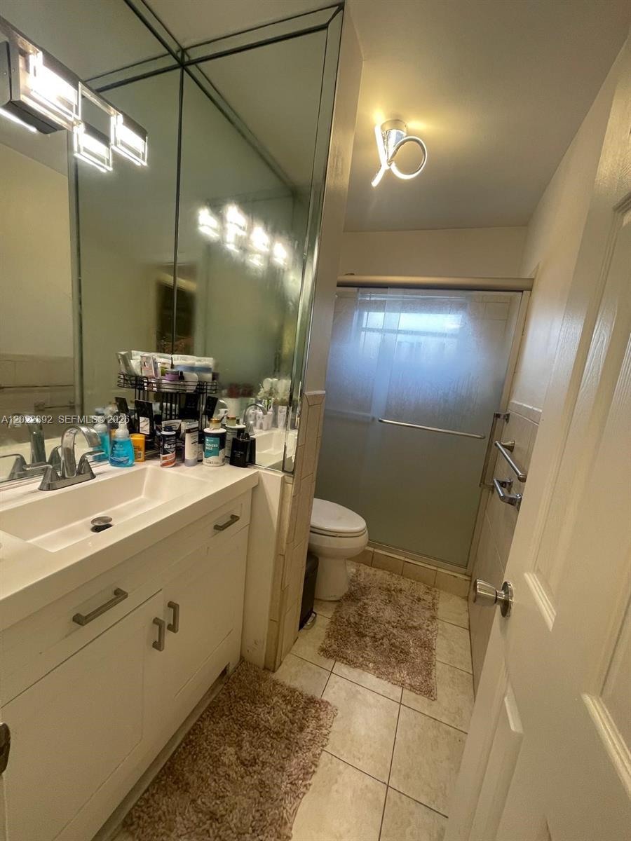 A bathroom features a white vanity, a large mirror, and a glass-enclosed shower area — 201 NE 14th Ave # 5A, Hallandale Beach FL 33009, HALLANDALE BEACH, FL