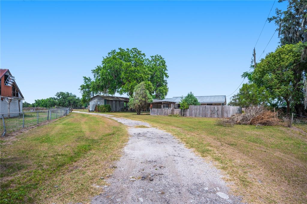 A gravel driveway leads toward a house and a barn on a grassy rural lot — 1616 MCGEE ROAD, PLANT CITY, FL