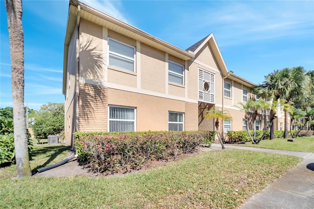 A two-story tan apartment building with brick accents and a landscaped front yard — 9942 TURF WAY UNIT 1, ORLANDO, FL