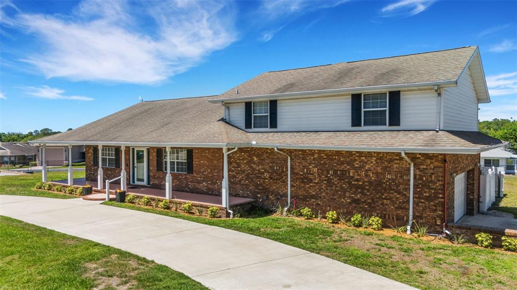 A two-story house with a brick facade, white siding, and a covered front porch — 5905 MAGNOLIA LANE, LAKELAND, FL
