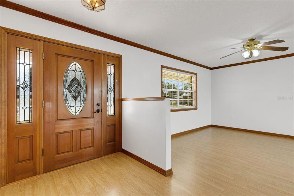 An entryway with light wood flooring, a wooden front door, and a half-wall partition — 5905 MAGNOLIA LANE, LAKELAND, FL