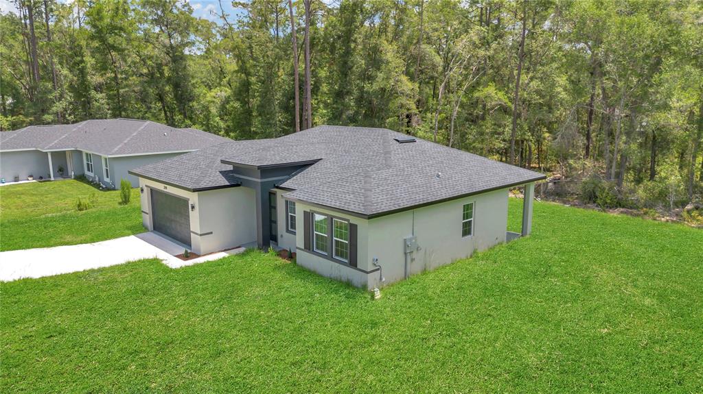 An aerial view of a single-story house with a gray roof and a concrete driveway — 219 E CALDWELL DRIVE, DUNNELLON, FL
