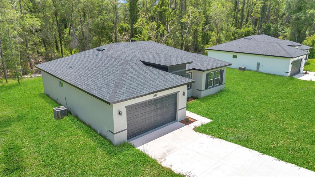 An aerial view shows a single-story house with a gray roof and a two-car garage — 219 E CALDWELL DRIVE, DUNNELLON, FL