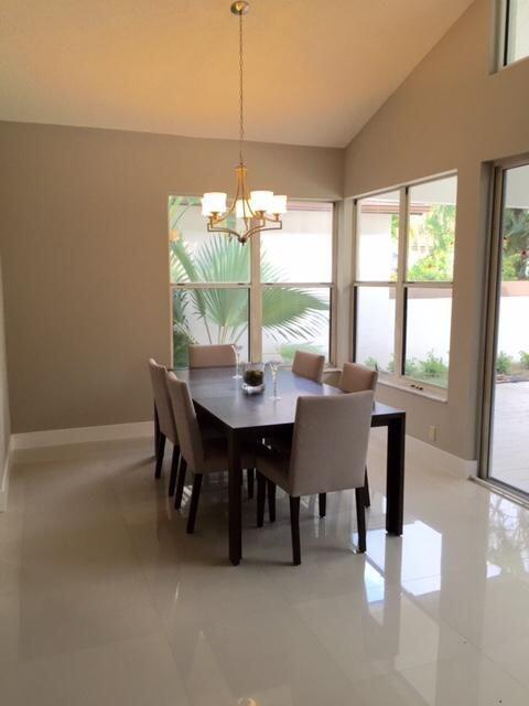 A dining room with a dark wood table, upholstered chairs, and a chandelier near windows — 5463 NW 20th Avenue, Boca Raton FL 33496, BOCA RATON, FL