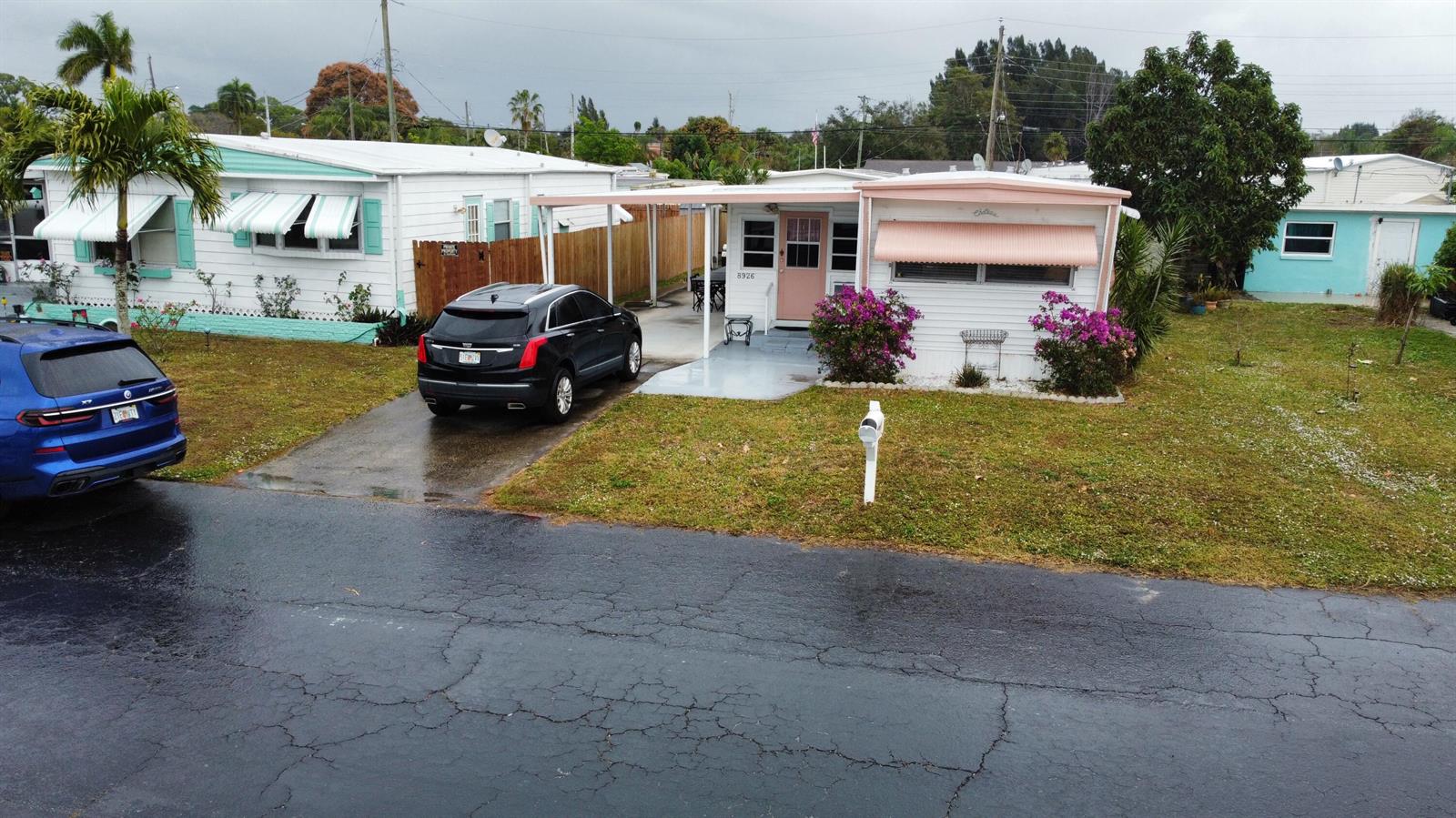 An exterior view of a white mobile home with a pink awning and driveway — 8926 Palm Street, Boynton Beach FL 33436, BOYNTON BEACH, FL
