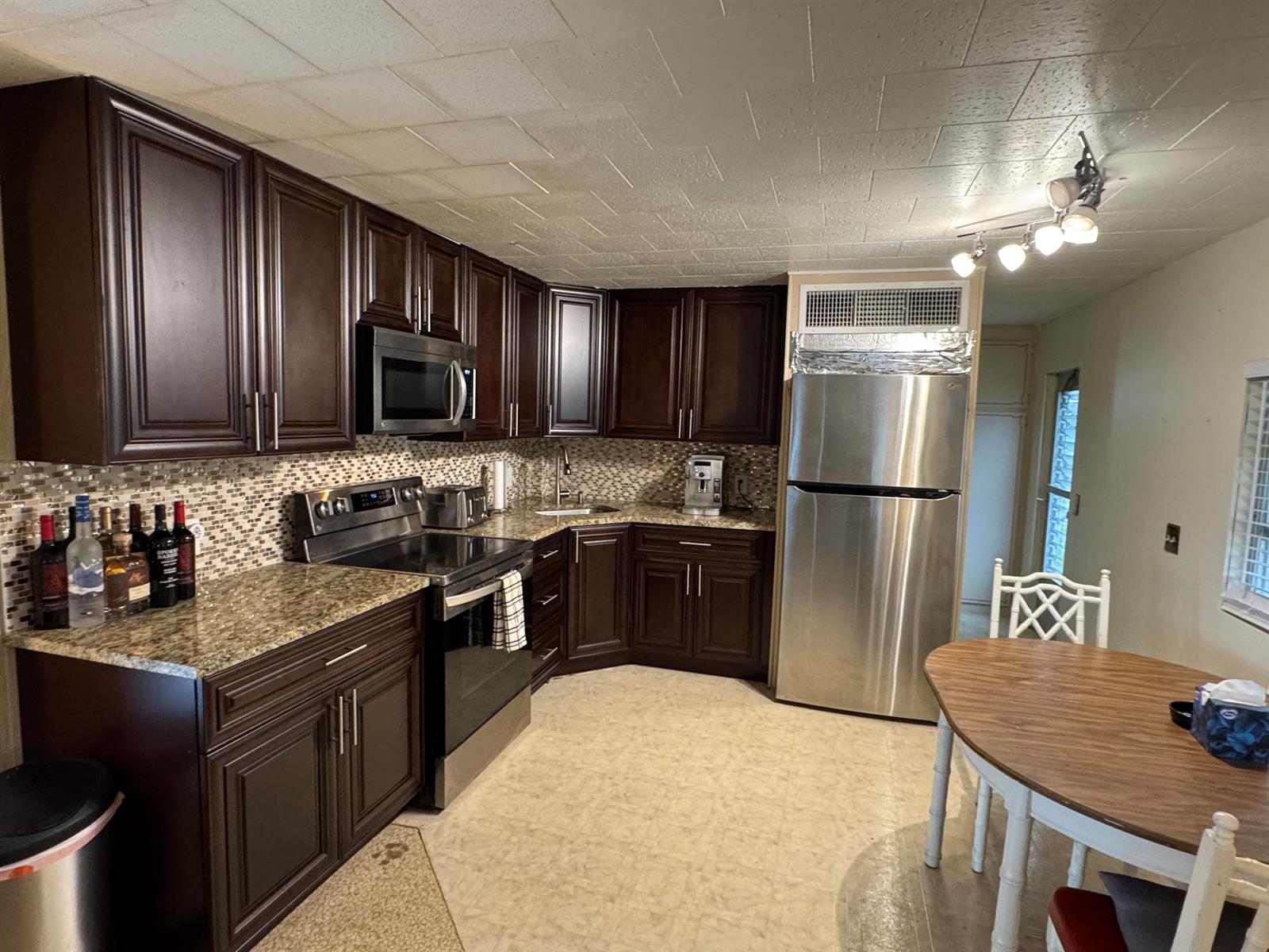 A kitchen features dark wood cabinets, granite countertops, stainless steel appliances, and a dining area — 8926 Palm Street, Boynton Beach FL 33436, BOYNTON BEACH, FL