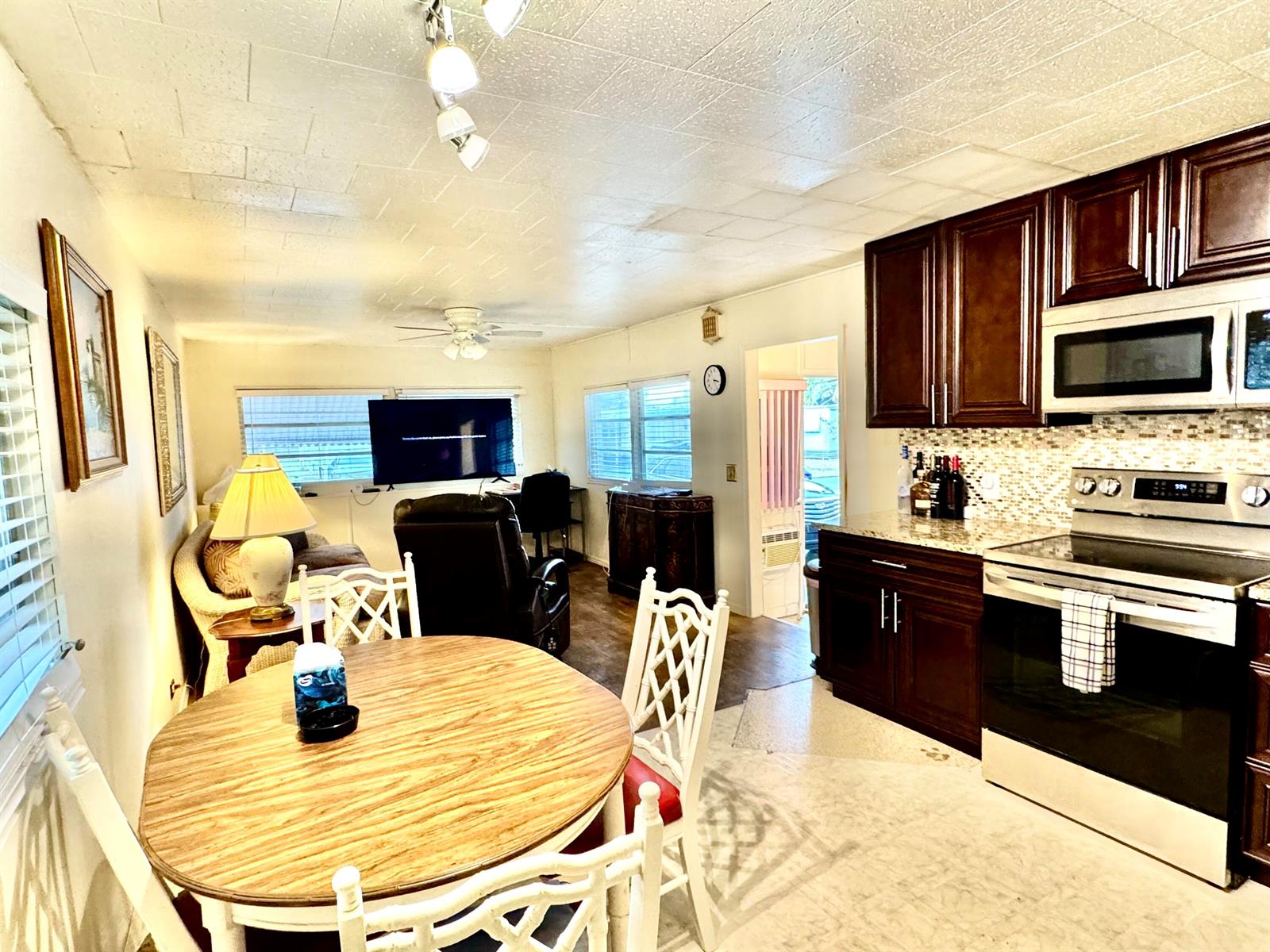 An open-concept kitchen and living area features dark wood cabinets, stainless appliances, and a dining table — 8926 Palm Street, Boynton Beach FL 33436, BOYNTON BEACH, FL
