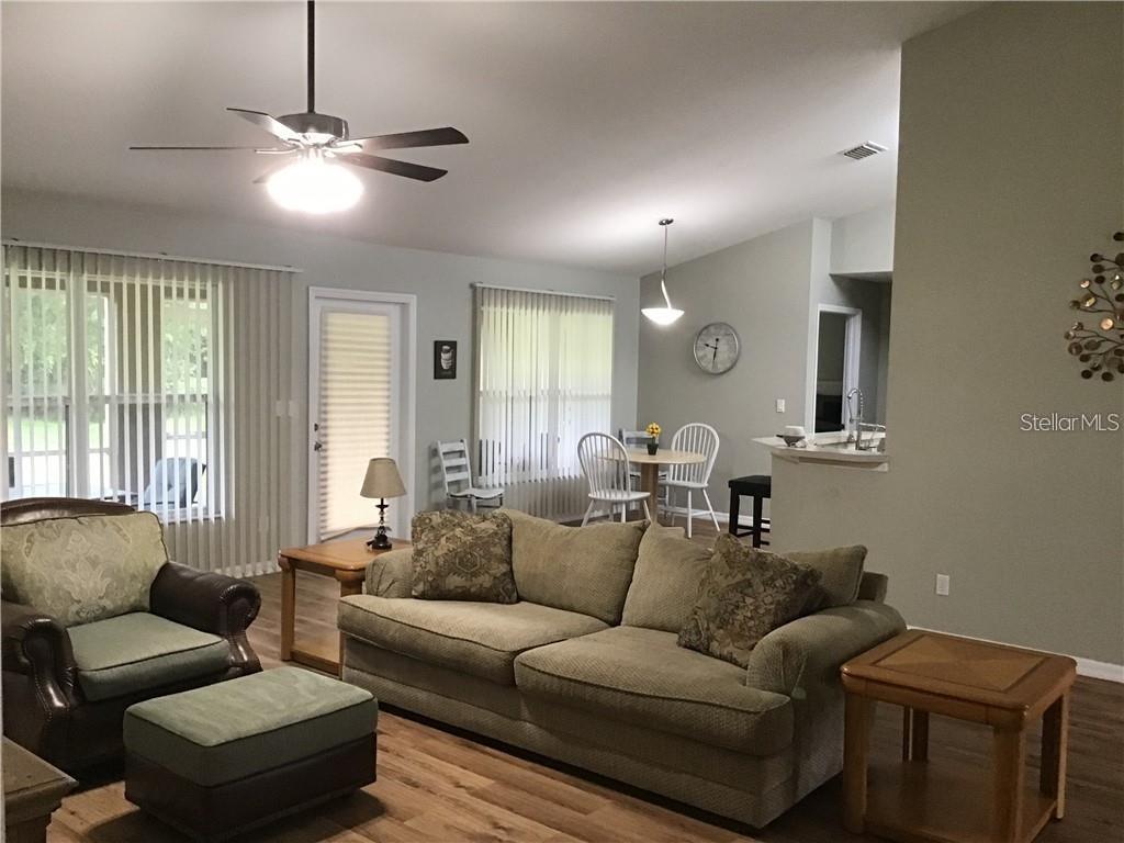 A living room with a sofa, armchair, ottoman, and an adjacent dining area — 2091 SNOWFLAKE LANE, NORTH PORT, FL