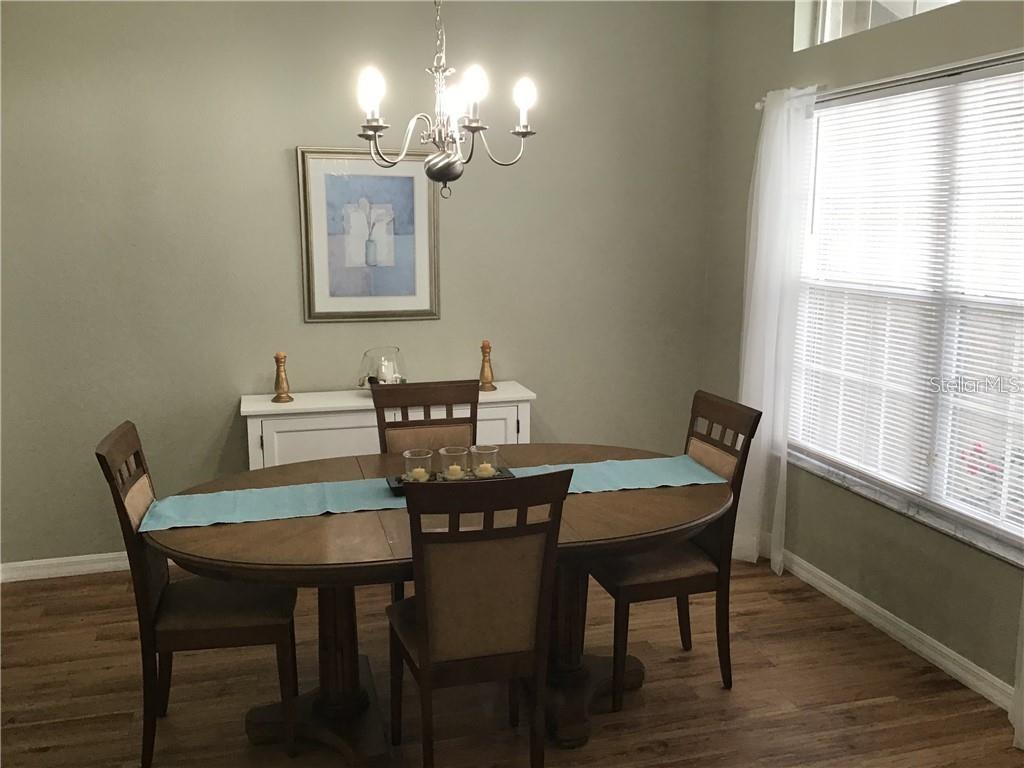 A dining room features a wooden table with four chairs, a chandelier, and a sideboard — 2091 SNOWFLAKE LANE, NORTH PORT, FL