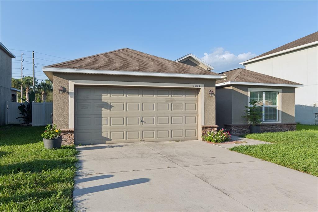 A single-story house with a tan stucco exterior, a two-car garage, and a concrete driveway — 13743 NEWPORT SHORES DRIVE, HUDSON, FL