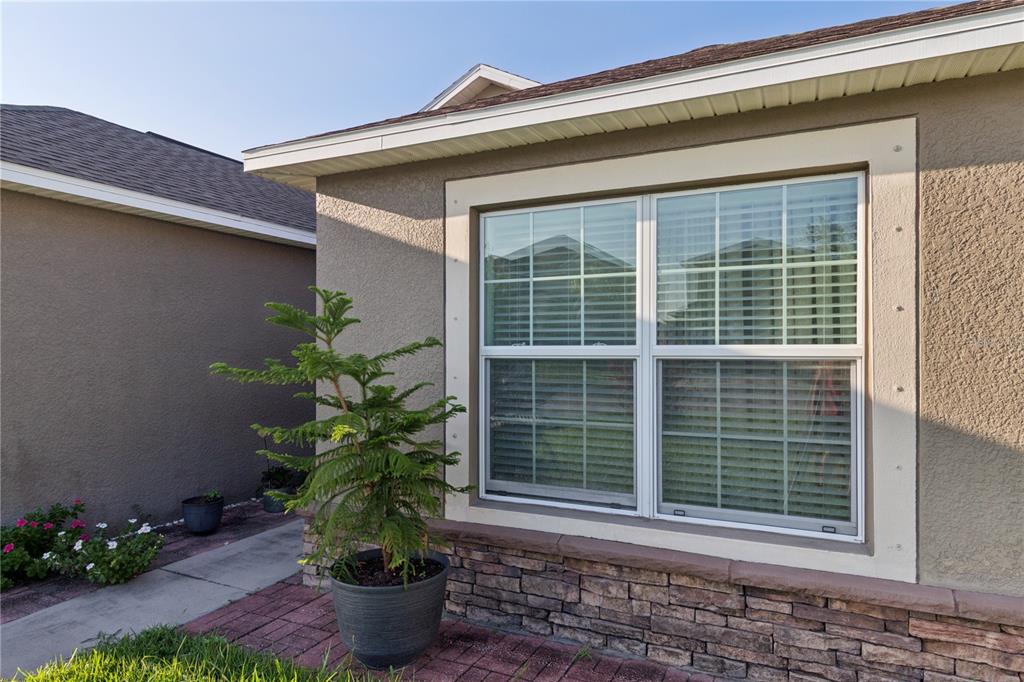 The exterior of a house features a window with stone veneer siding and a potted plant — 13743 NEWPORT SHORES DRIVE, HUDSON, FL