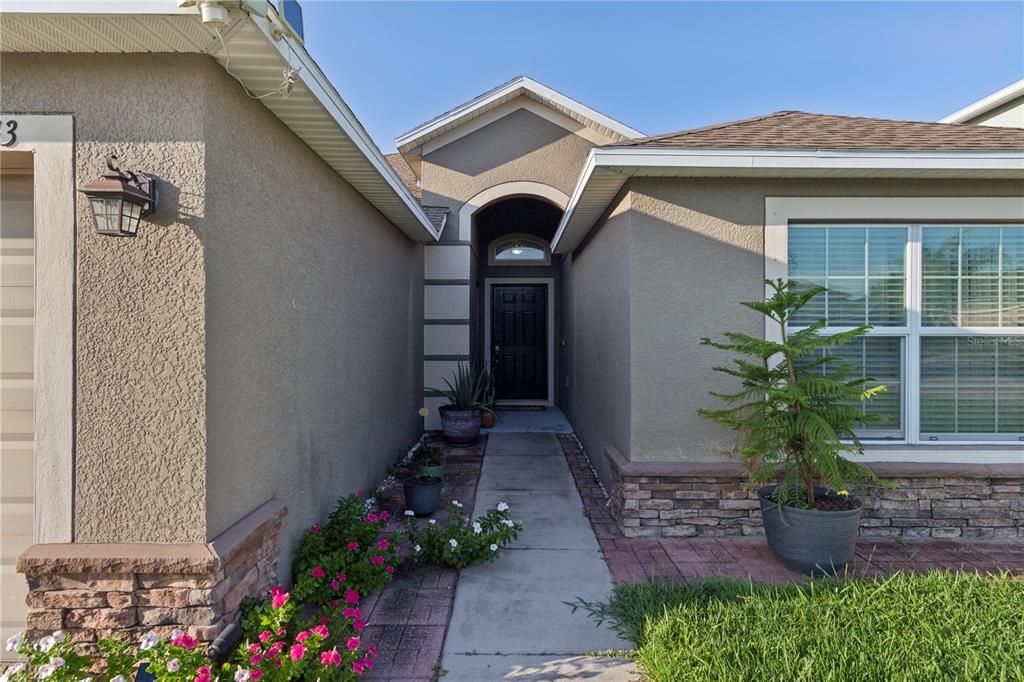The exterior of a house features a concrete walkway leading to a dark front door — 13743 NEWPORT SHORES DRIVE, HUDSON, FL