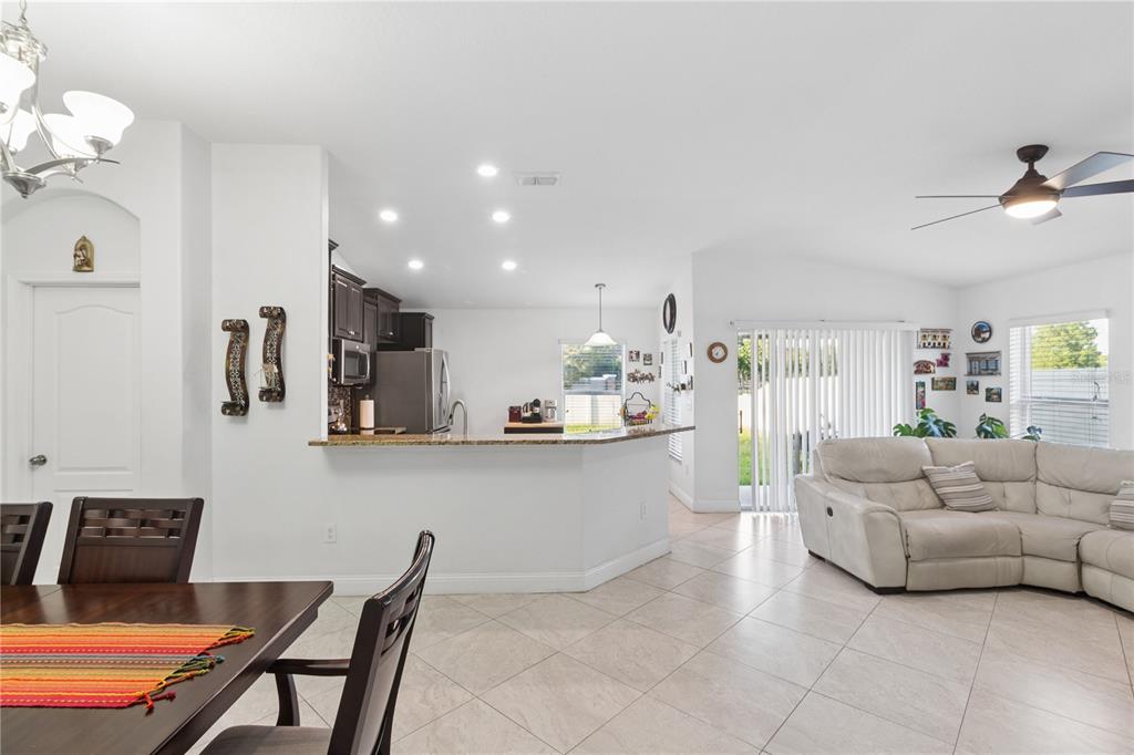 An open-concept kitchen with granite countertops overlooks a living area with tile flooring — 13743 NEWPORT SHORES DRIVE, HUDSON, FL