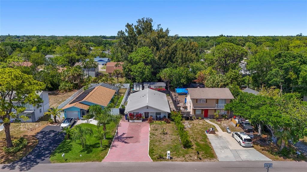 A covered patio features brick pavers, two wicker chairs with ottomans, and a Buddha statue — 831 WINTER GARDEN DRIVE, SARASOTA, FL