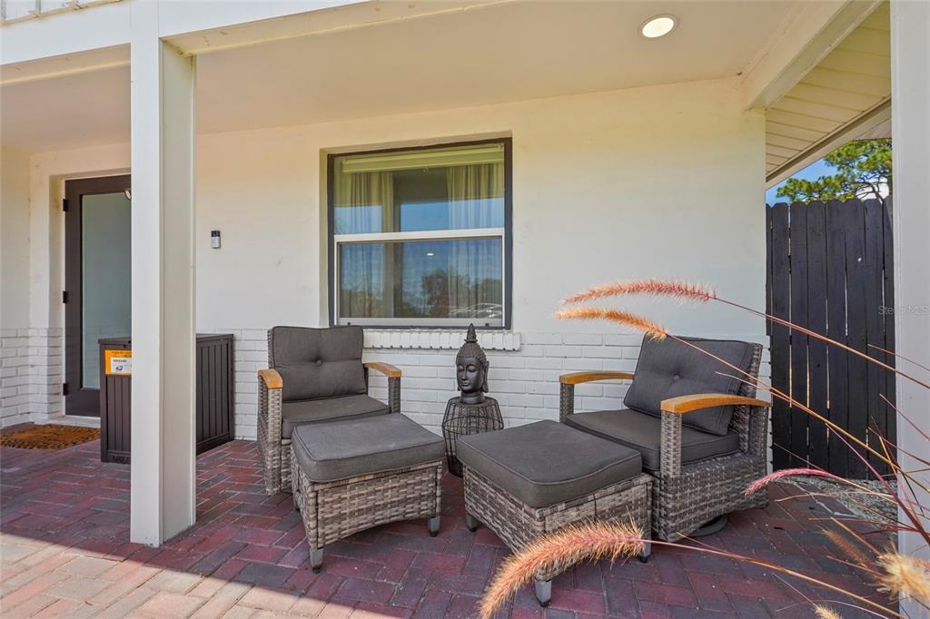 A white kitchen features stainless steel appliances, marble-style backsplash, and a breakfast bar with stools — 831 WINTER GARDEN DRIVE, SARASOTA, FL