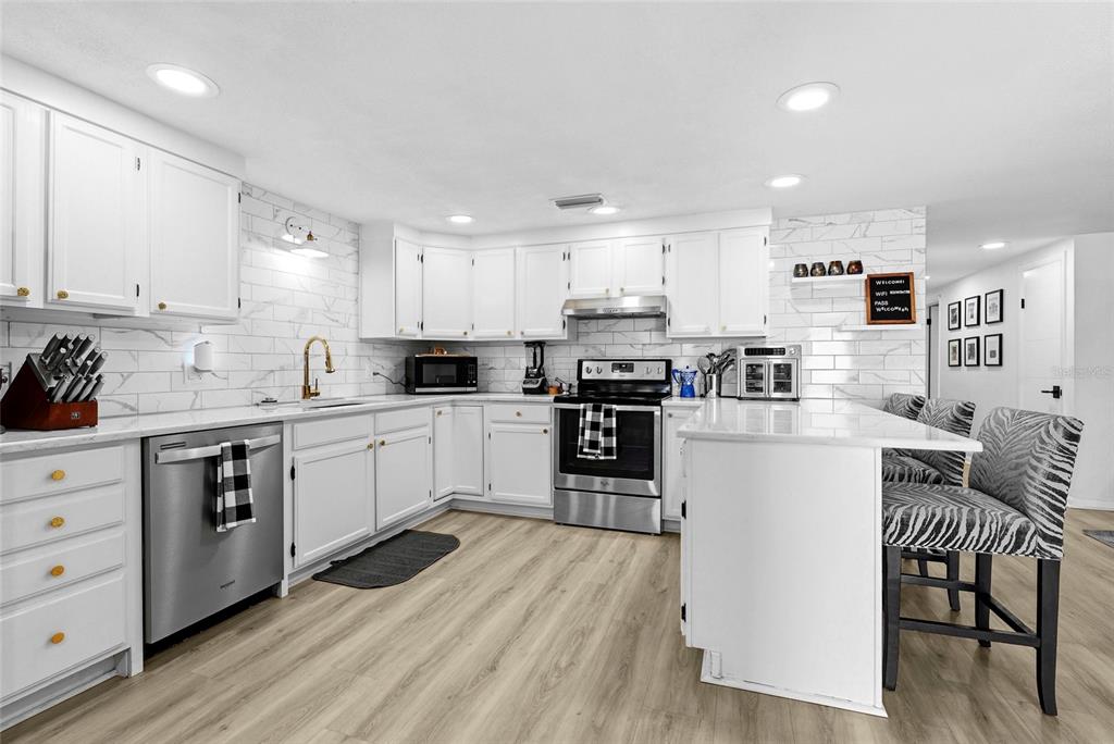 A dining area features a round table, black chairs, a wine cooler, and stainless steel refrigerator — 831 WINTER GARDEN DRIVE, SARASOTA, FL