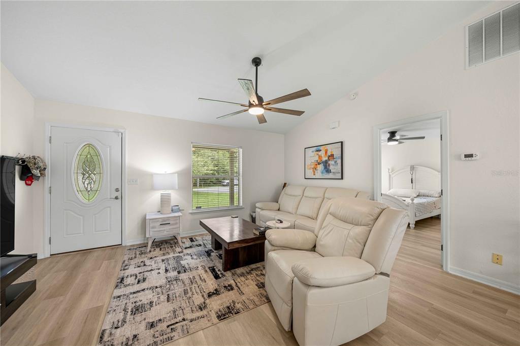 A living room features light wood flooring, a white sofa, and a ceiling fan — 80 PECAN RUN COURSE, OCALA, FL