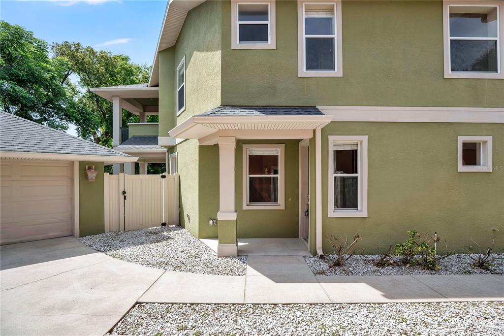 A two-story green stucco house features a covered entryway, a garage, and a white fence — 2403 S SHINE AVENUE UNIT B, ORLANDO, FL