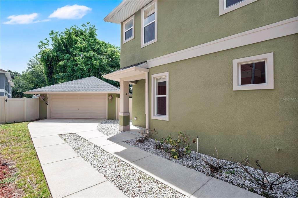 A side view of a two-story green house with a detached garage and concrete walkway — 2403 S SHINE AVENUE UNIT B, ORLANDO, FL