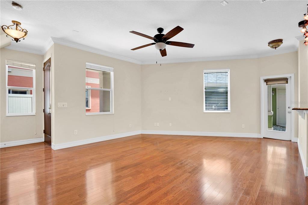 An empty room with hardwood floors, a ceiling fan, and multiple windows and doors — 2403 S SHINE AVENUE UNIT B, ORLANDO, FL