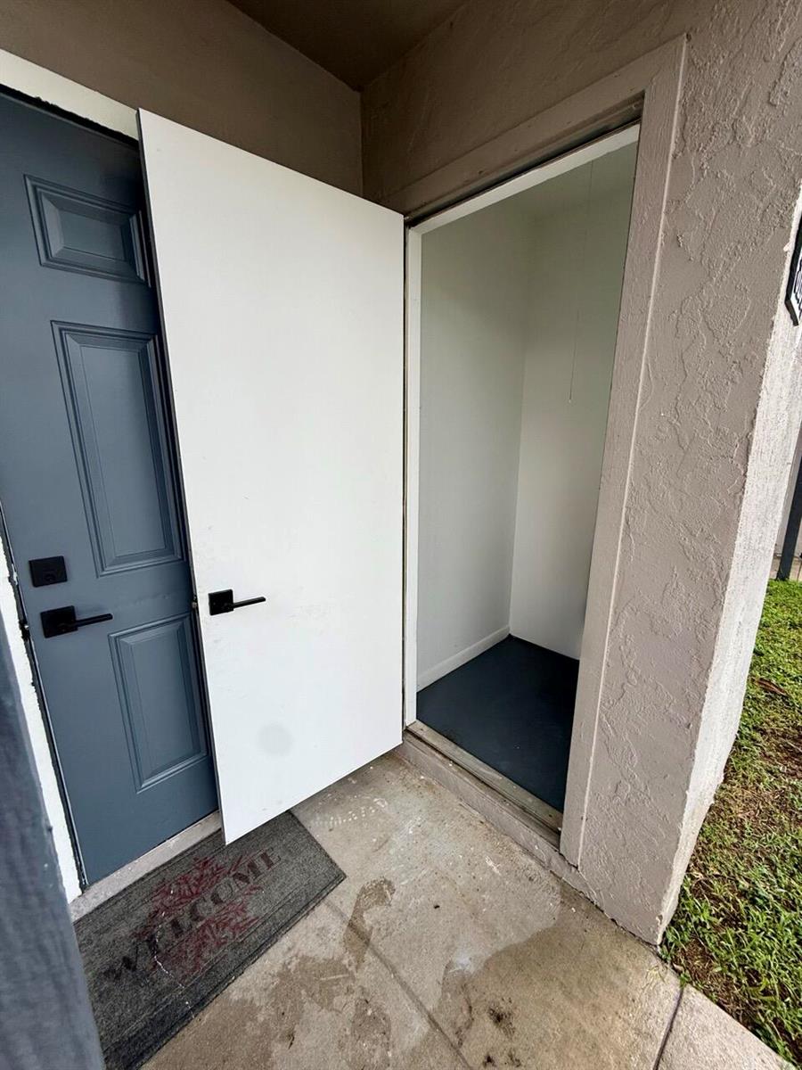 An open white storage closet door sits next to a dark blue front entry door — 3104 Poolside Drive, FL 33463, FL