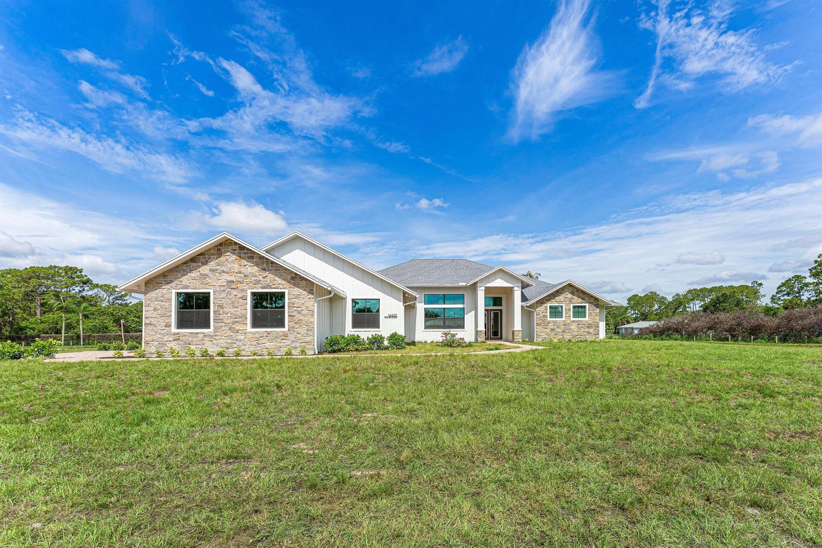 A single-story house with stone and white siding features a large front lawn — 16631 132nd Terrace N, Jupiter FL 33478, JUPITER, FL