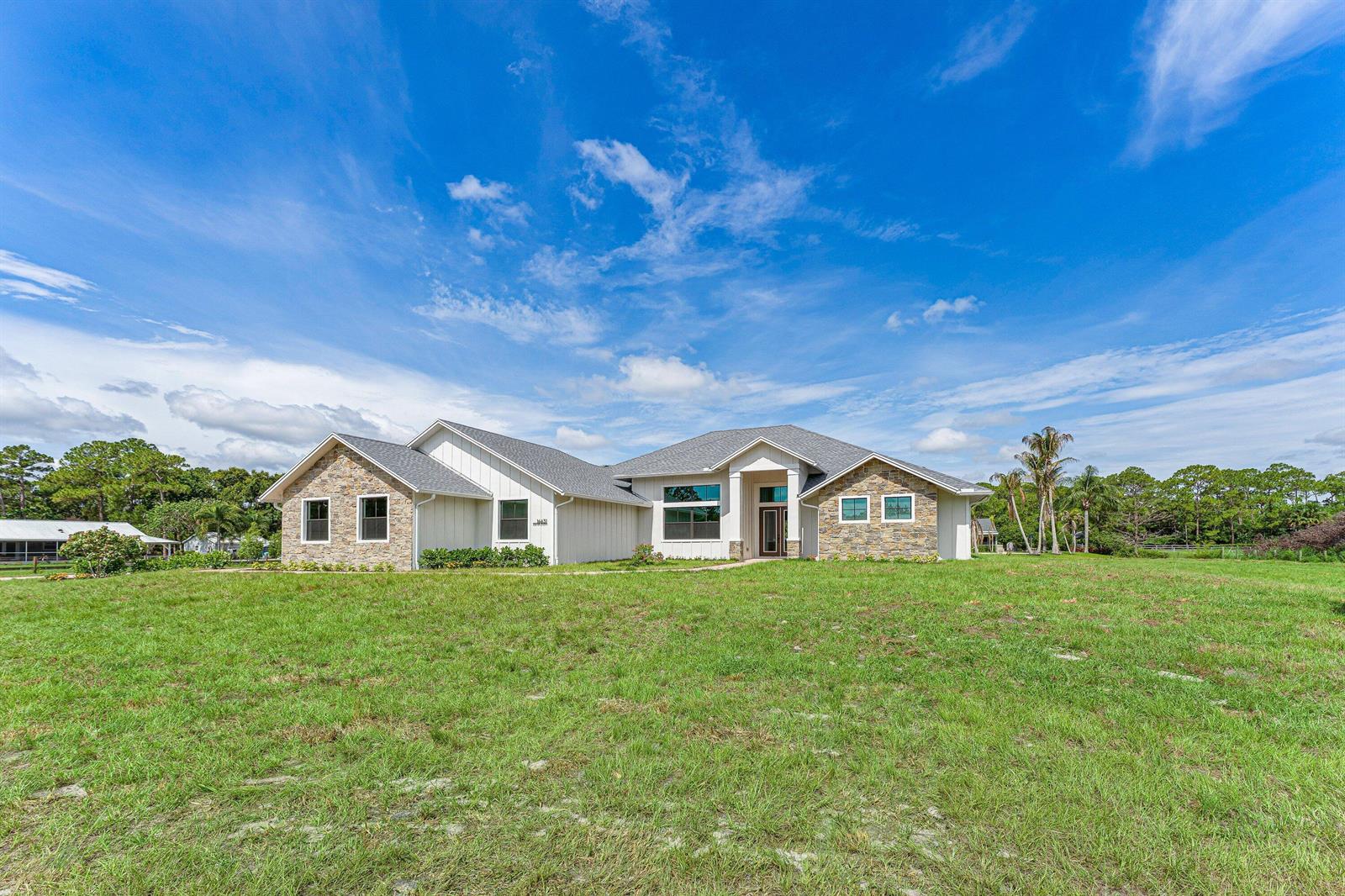 A single-story house with stone and white siding sits on a large grassy lot — 16631 132nd Terrace N, Jupiter FL 33478, JUPITER, FL