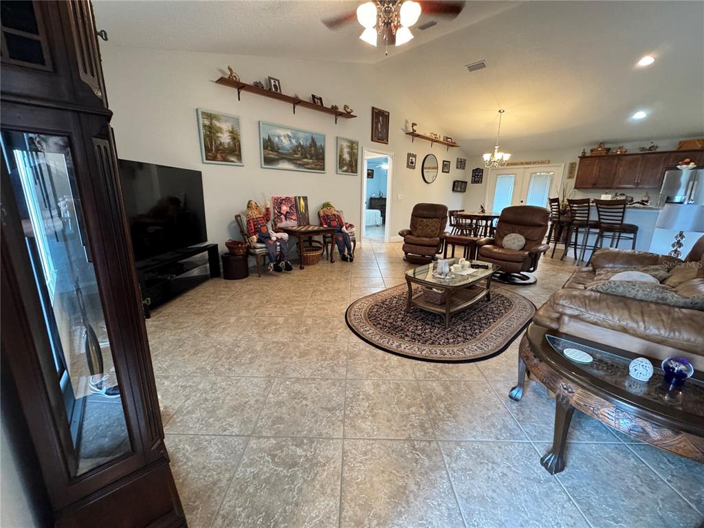 A spacious living room features tile flooring, leather furniture, and a vaulted ceiling — 8340 SE 159TH LANE, SUMMERFIELD, FL