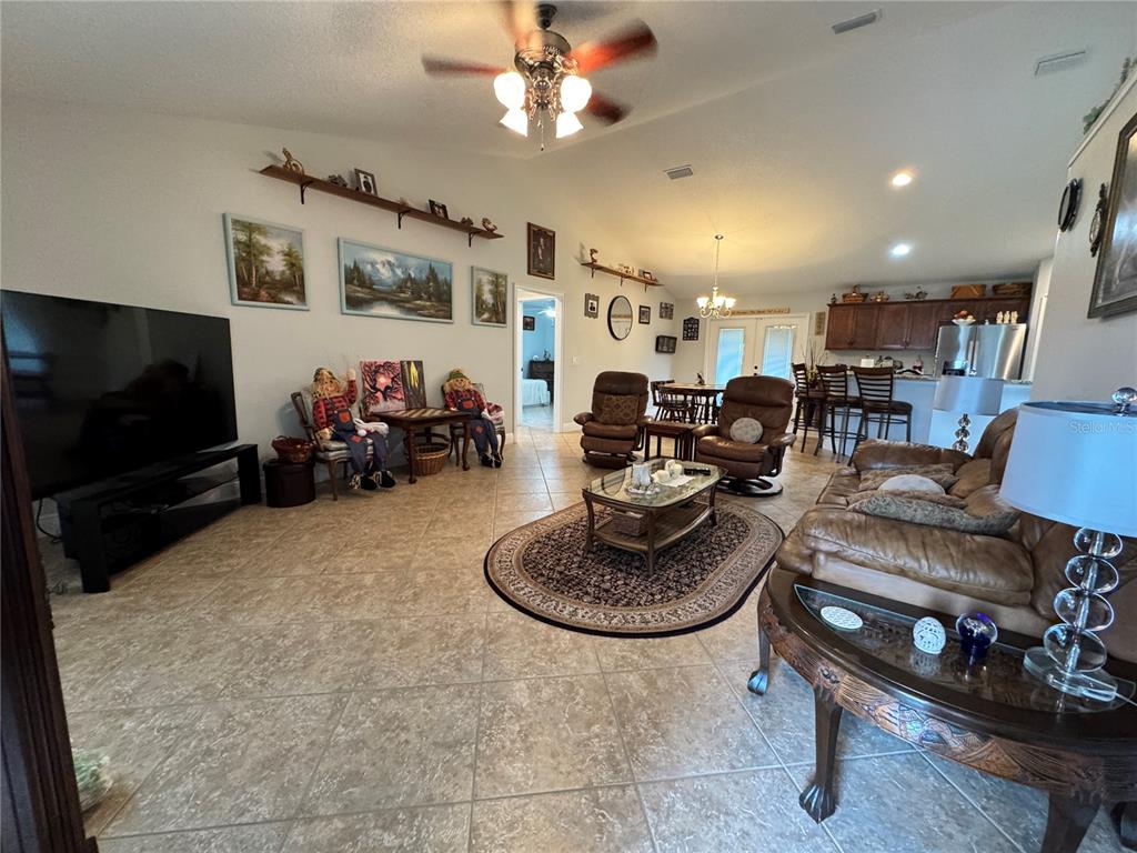 A spacious open-concept living room features tile flooring, a vaulted ceiling, and a kitchen area — 8340 SE 159TH LANE, SUMMERFIELD, FL