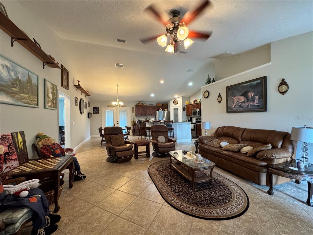 An open-concept living room features tile flooring, a ceiling fan, and a brown leather sofa — 8340 SE 159TH LANE, SUMMERFIELD, FL